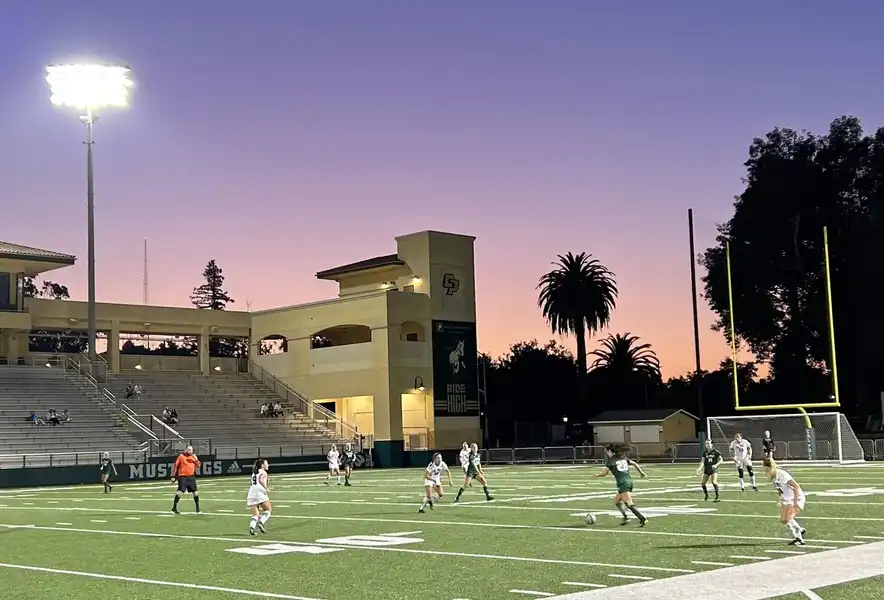 Campo de fútbol al atardecer con cielo naranja